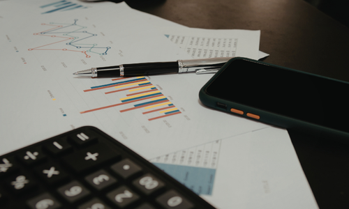 Business financial reports with charts, calculator and smartphone on a desk